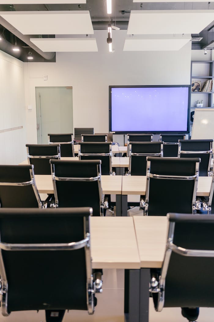 Empty conference room featuring stylish office chairs and a blank presentation screen.